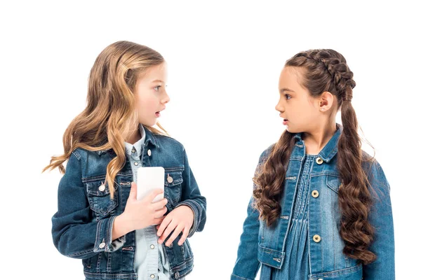 Two surprised kids with smartphone looking at each other isolated on white — Stock Photo