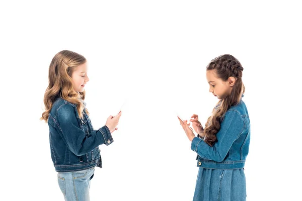 Due bambini in denim vestiti utilizzando smartphone isolati su bianco — Foto stock