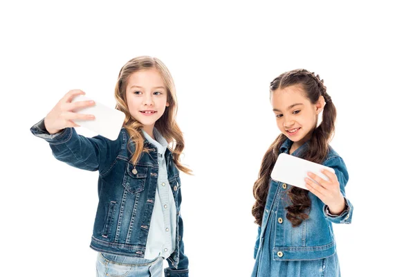 Dos niños en ropa de mezclilla tomando selfie en blanco - foto de stock