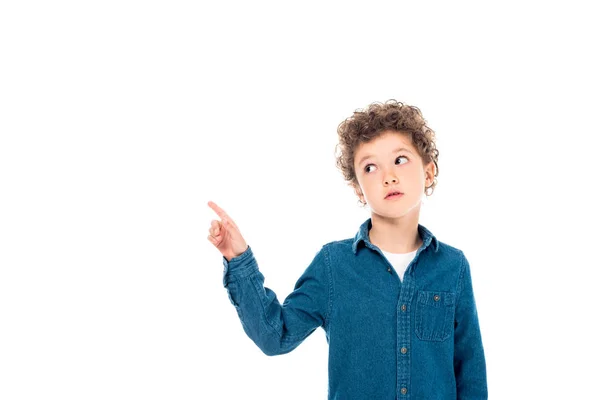 Pensive curly kid in denim shirt pointing with finger isolated on white — Stock Photo