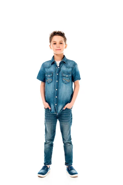 Полный вид на ребенка в джинсовой одежде стоя с руками в карманах изолированы на белом — стоковое фото