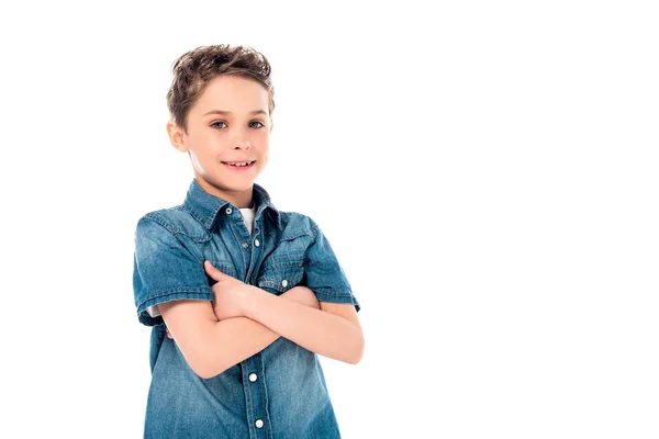 Улыбающийся ребенок в джинсовой рубашке позирует со скрещенными руками, изолированными на белом — стоковое фото