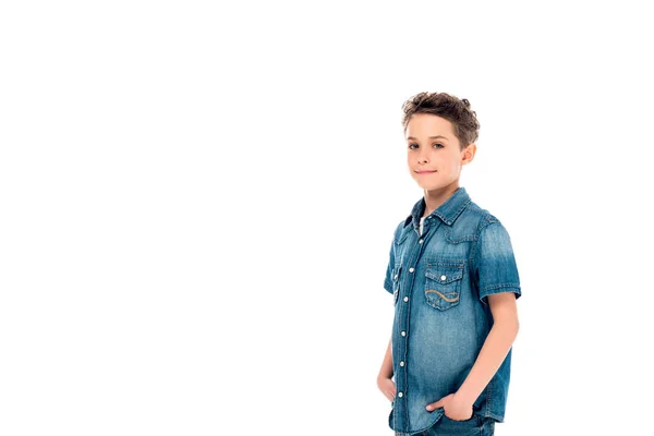 Niño en camisa de mezclilla posando con las manos en bolsillos aislados en blanco - foto de stock