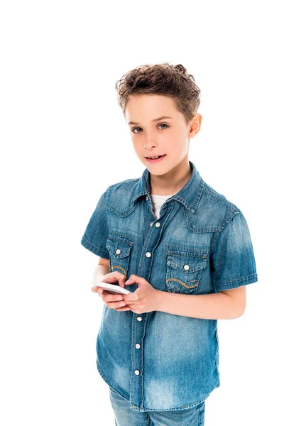 Niño sonriente en camisa de mezclilla usando teléfono inteligente aislado en blanco - foto de stock
