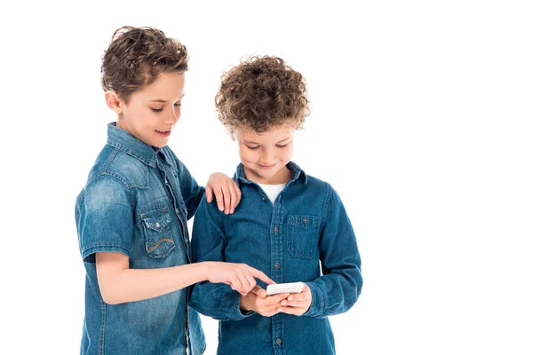 Duas crianças em camisas jeans usando smartphone isolado no branco — Fotografia de Stock