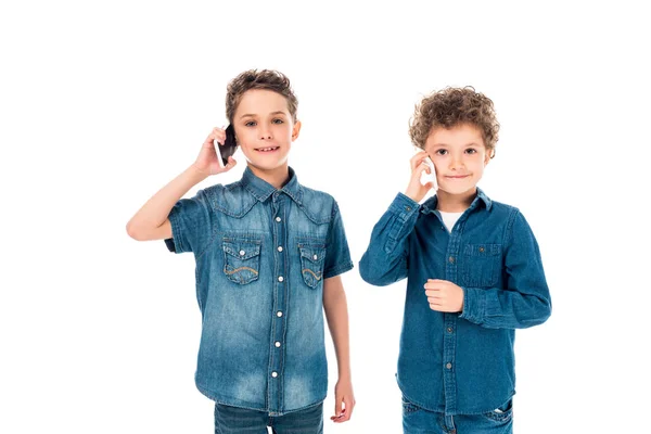 Vista frontal de dos niños hablando en teléfonos inteligentes aislados en blanco - foto de stock