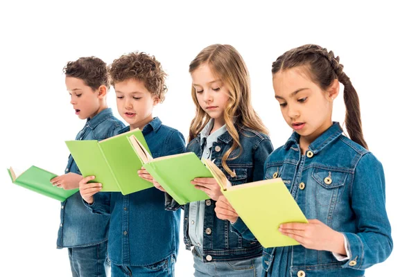 Cuatro niños sorprendidos en ropa de mezclilla leyendo libros aislados en blanco - foto de stock