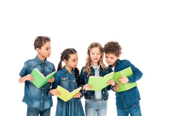 Cuatro niños en ropa de mezclilla leyendo libros aislados en blanco - foto de stock