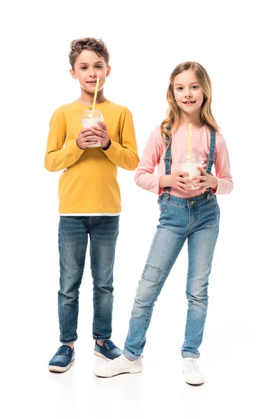 Вигляд на повну довжину двох дітей, що тримають молочні коктейлі ізольовані на білому — стокове фото