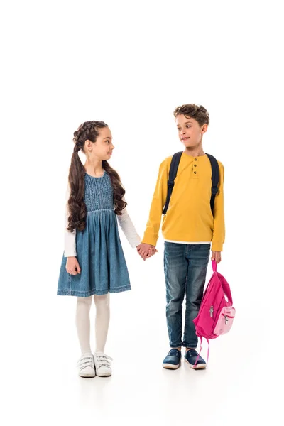 Full length view of schoolchildren with backpacks holding hands isolated on white — Stock Photo