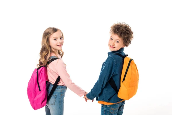 Schulkinder mit Rucksäcken, die sich an den Händen halten und isoliert auf Weiß zurückblicken — Stockfoto