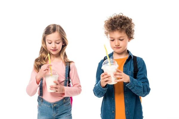 Deux écoliers avec des sacs à dos tenant milkshakes isolés sur blanc — Photo de stock