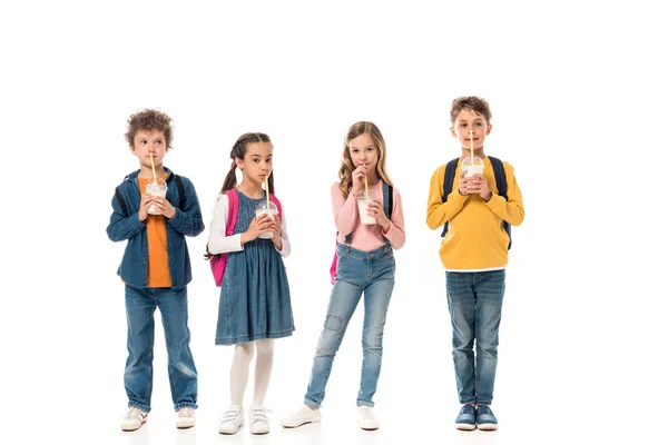 Full length view of schoolchildren drinking milkshakes isolated on white — Stock Photo