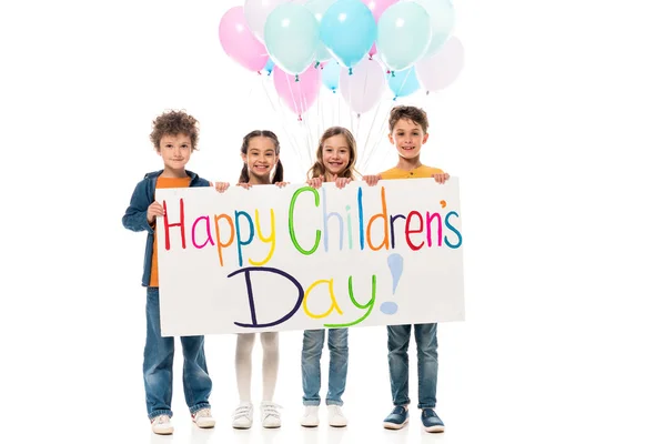 Повнометражний вигляд дітей, що тримають різнокольорові кульки та плакат ізольовані на білому — стокове фото