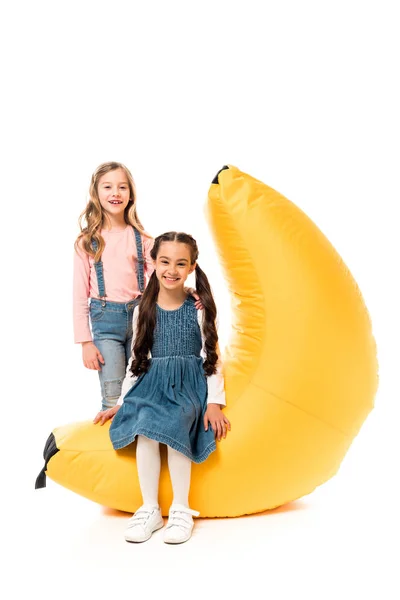 Duas crianças sorridentes com cadeira de saco de feijão no branco — Fotografia de Stock