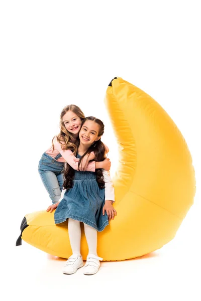 Two smiling kids with bean bag chair on white — Stock Photo