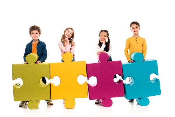 Full length view of kids with colorful jigsaw puzzles on white — Stock Photo