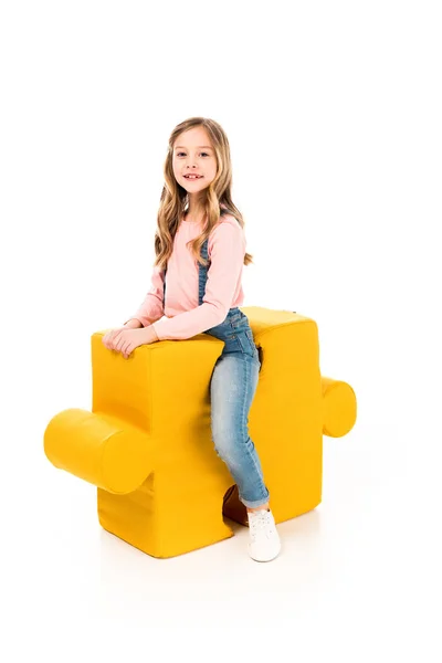 Smiling kid sitting on big jigsaw puzzle on white — Stock Photo