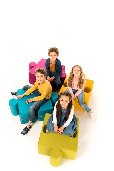 Overhead view of kids sitting on jigsaw puzzles on white — Stock Photo