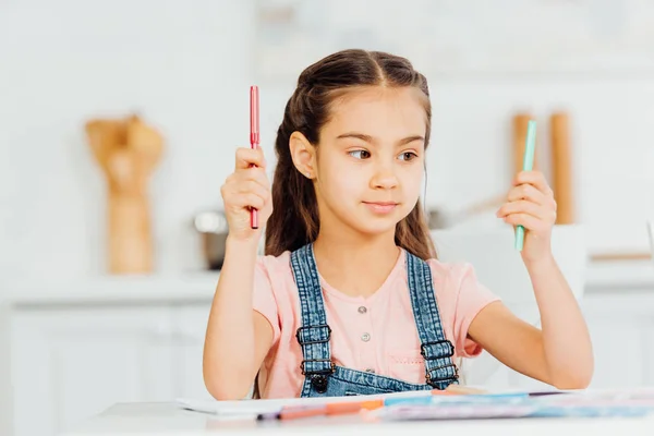 Cute kid choosing between turquoise and red felt pens at home — Stock Photo