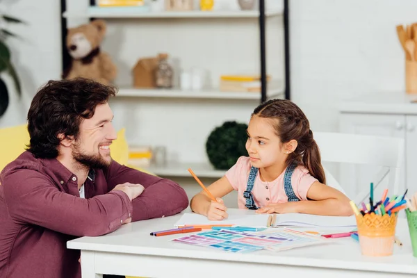 Glücklicher Vater und fröhliche und süße Tochter, die sich zu Hause anschauen — Stockfoto