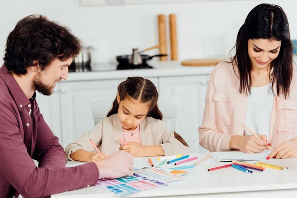 Весёлая мама и папа рисуют с милой дочкой дома — стоковое фото