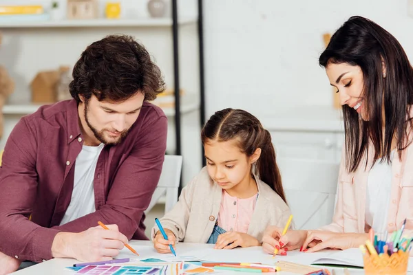 Mãe feliz desenho perto bonito filha e marido em casa — Fotografia de Stock