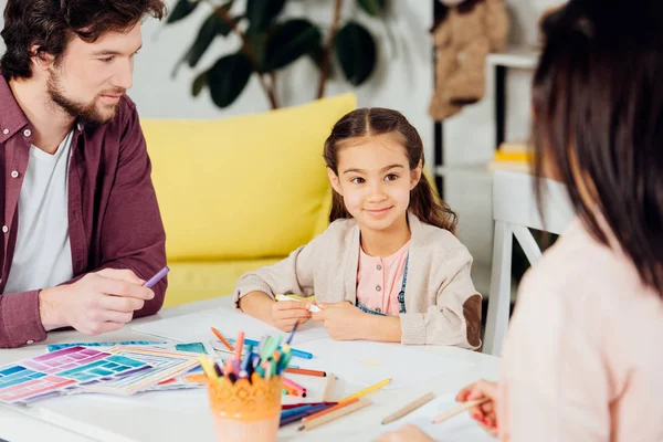 Selective focus of cute daughter looking at brunette mother near father — Stock Photo