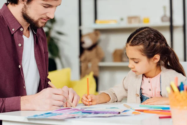 Selective focus of cute daughter drawing with handsome father — Stock Photo