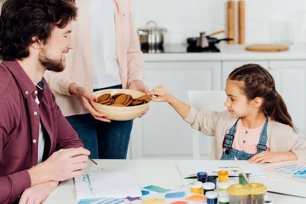 Abgeschnittene Ansicht der Mutter hält Schüssel mit leckeren Keksen ordentlich Tochter und Ehemann — Stockfoto