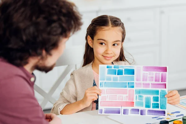 Foco seletivo de criança alegre segurando papel com listras coloridas perto do pai — Fotografia de Stock