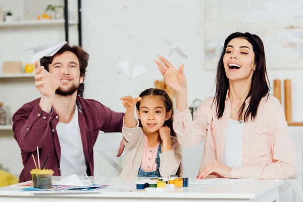 Вибірковий фокус щасливої сім'ї, дивлячись на літаючі паперові площини вдома — стокове фото