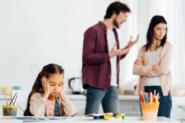 Enfoque selectivo de niño molesto cerca de padre peleando con la madre - foto de stock