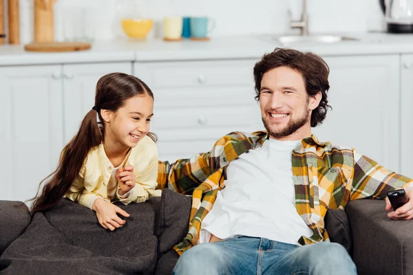 Счастливый ребенок улыбается рядом веселый отец сидит на диване — стоковое фото