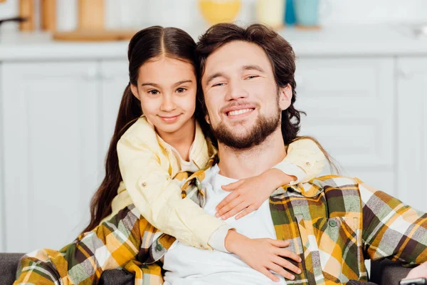Счастливая дочь обнимает весёлого бородатого отца дома — стоковое фото