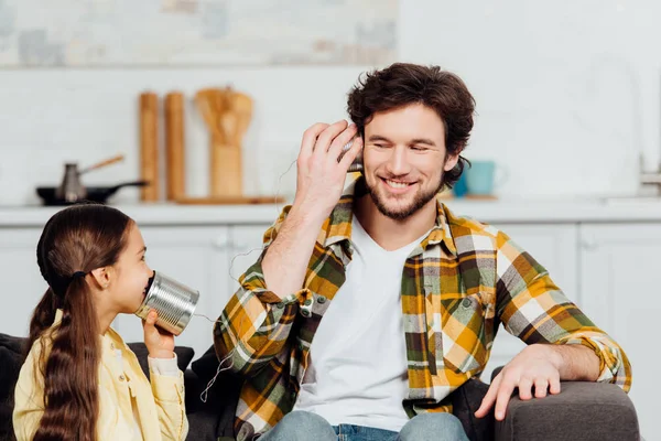 Happy daughter talking on can phone and cheerful father listening at home — Stock Photo