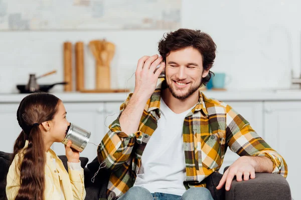 Glückliche Tochter telefoniert und fröhlicher Vater hört zu Hause zu — Stockfoto