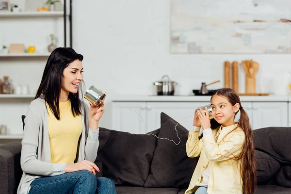 Cheerful mother talking while holding tin can and playing with happy daughter — Stock Photo