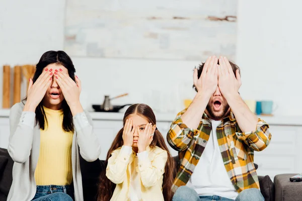 Schockierte Familie verdeckt Gesicht beim Fernsehen zu Hause — Stockfoto