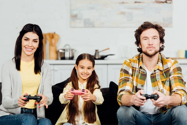 Lindo y feliz niño jugando videojuego con los padres en casa - foto de stock