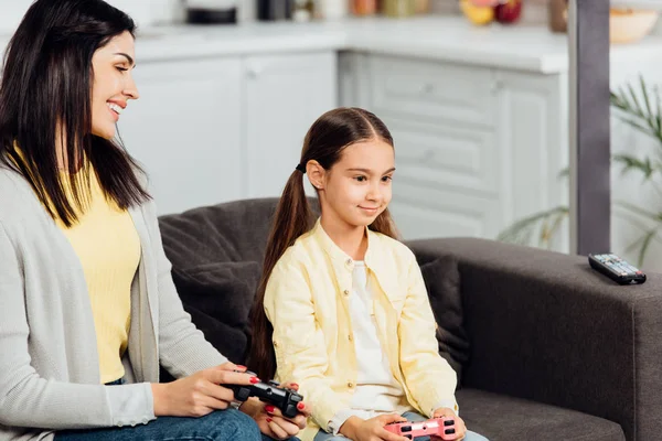 Happy kid playing video game with cheerful mother at home — Stock Photo