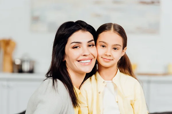 Happy child looking at camera with cheerful mother at home — Stock Photo