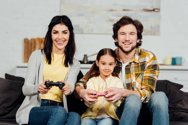 Красивый мужчина, сидящий рядом со счастливым ребенком и играющий дома в видеоигру — стоковое фото