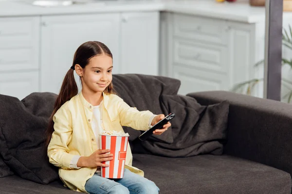 Garoto alegre segurando controlador remoto e assistindo filme em casa — Fotografia de Stock