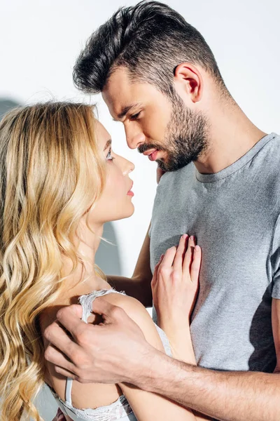 Schöner bärtiger Mann schaut attraktive blonde Frau auf weißem Grund an — Stock Photo