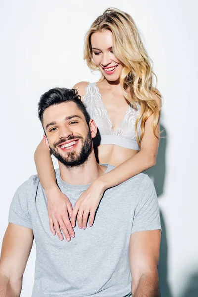 Feliz rubia chica mirando guapo y alegre hombre en blanco - foto de stock