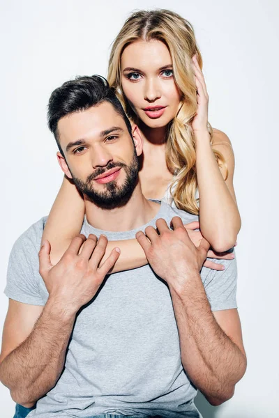 Beautiful blonde girl looking at camera while hugging handsome man on white — Stock Photo