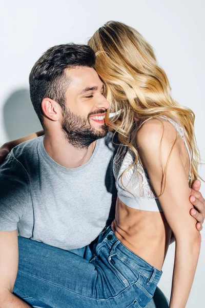 Homme barbu joyeux souriant tout en étant assis avec une fille blonde sur blanc — Photo de stock