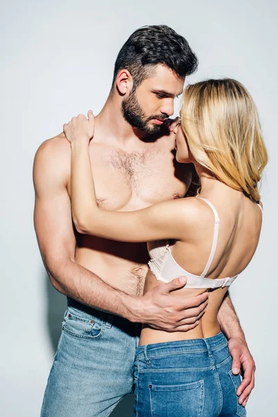 Muscular e sem camisa homem olhando para mulher loira no sutiã no branco — Fotografia de Stock