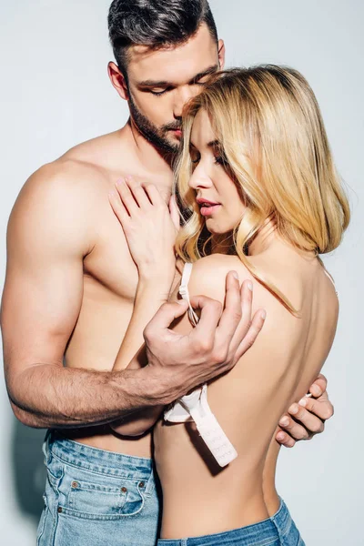 Hemdloser Mann zieht sexy blonde junge Frau auf Weiß aus — Stockfoto